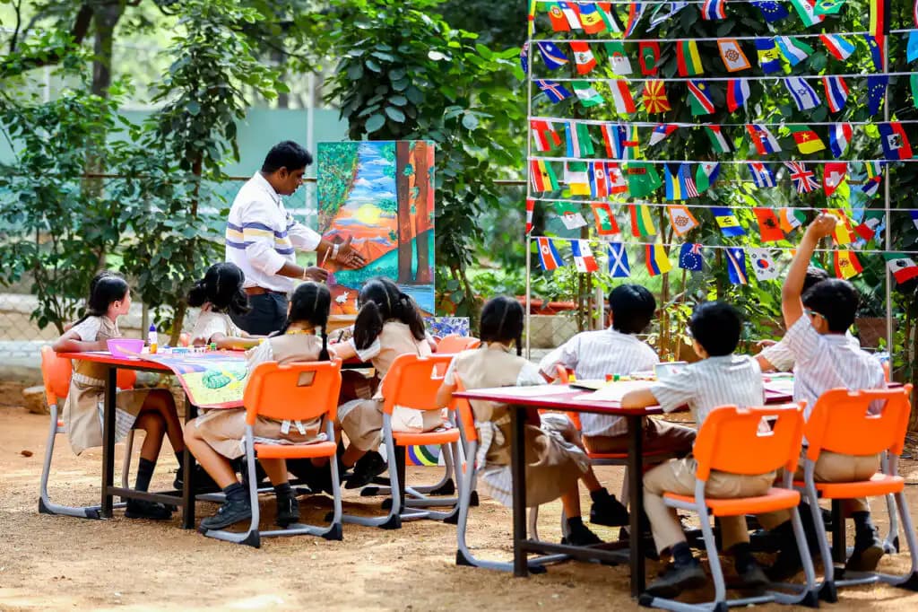 Students making art outdoors with a teacher at Suchitra